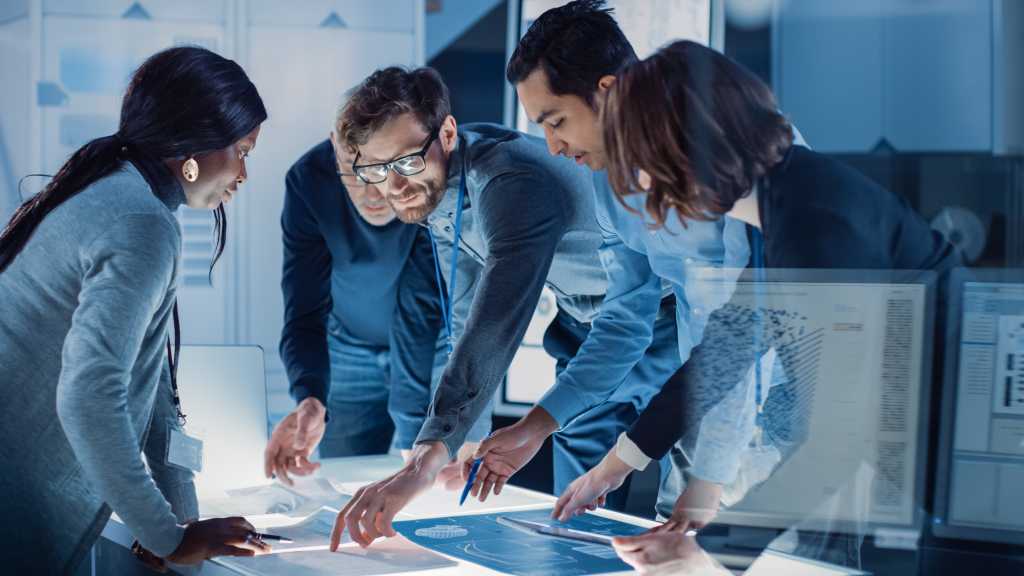 Engineers Meeting in Technology Research Laboratory: Engineers, Scientists and Developers Gathered Around Illuminated Conference Table, Talking and Finding Solution Inspecting Industrial Engine Design